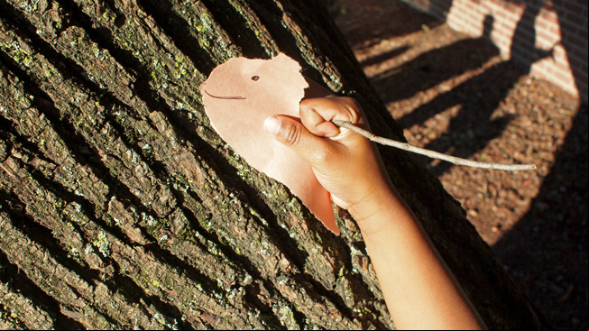 Boy hiding animal art against tree