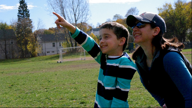 Parent and boy point at sky