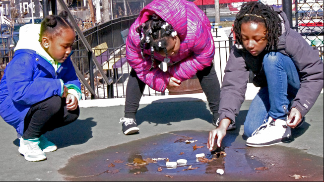 Girl floats object in puddle