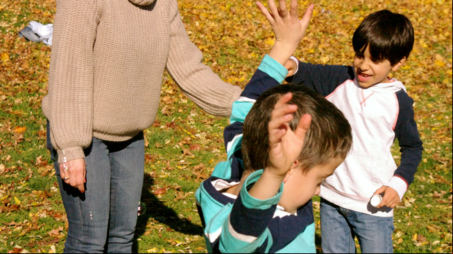Kids pretend to withstand wind